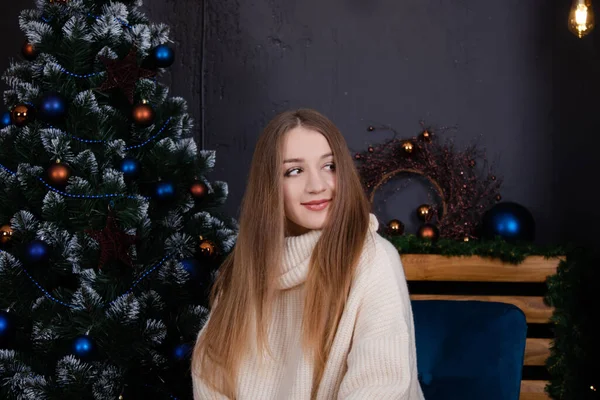 Charming brunette woman in knitted sweater near christmas tree with blue decor. happy new year theme. cozy holidays and celebrations — стоковое фото