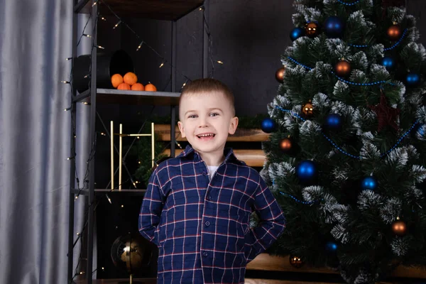 Little blonde boy near christmas tree in dark room with blue decoration. happy new year. christmas eve — Zdjęcie stockowe