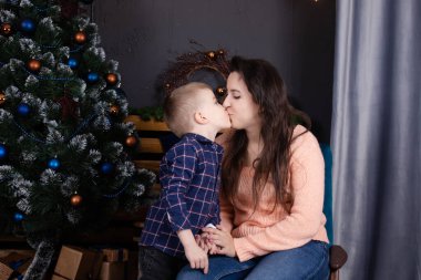 Merry Christmas and happy holidays. loving single mother with cheerful son play and cuddle near Christmas decoration, tree and gifts. Happy family, parent and child have fun on new year eve