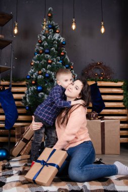 little toddler boy with woman near christmas tree and decoration. son and mother on christmas eve. new year. single mother. incomplete family