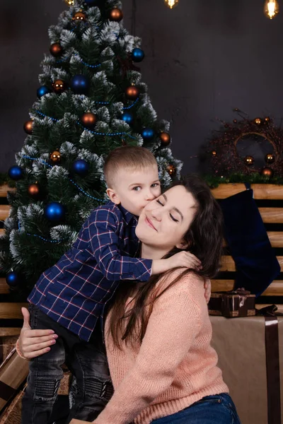 Little toddler boy with woman near christmas tree and decoration. son and mother on christmas eve. new year. single mother. incomplete family — Stockfoto