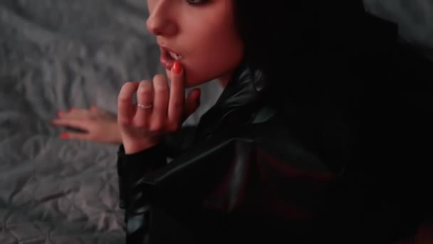 Sexy mujer morena confiada en ropa interior roja y chaqueta de cuero en la cama gris — Vídeo de stock