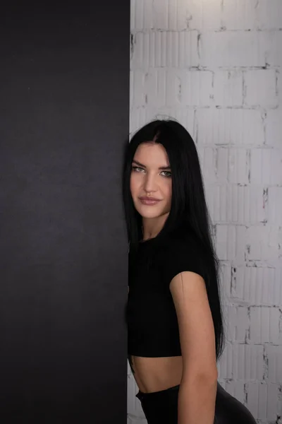 Sexy brunetka kobieta w czerni na tle białej cegły ściany. kobiecy portret mody — Zdjęcie stockowe