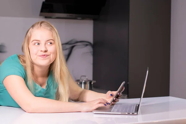 Joven empresaria en verde usando smartphone. En el escritorio está el portátil. Chica trabajando, aprendiendo en línea. Redes sociales, red. Marketing online, educación. —  Fotos de Stock