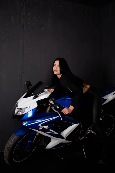 Seksowna kobieta w czarnych skórzanych ubraniach na niebieskim motocyklu. Kobieta kierowca. motocykl sportowy — Zdjęcie stockowe