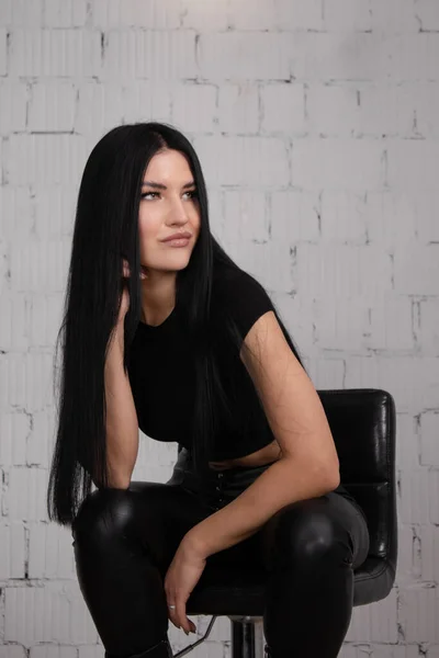 Sexy brünette Frau in schwarz vor weißem Backsteinhintergrund. Frauenmodeporträt — Stockfoto