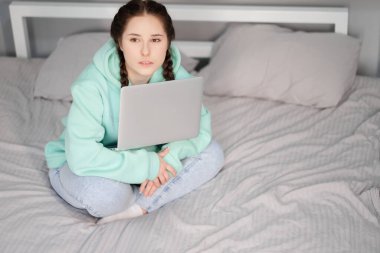 Uzaktan kumandalı ya da evden uzak çalışmalı. Yatakta dizüstü bilgisayarlı esmer bir kadın. Karantina kısıtlamaları. covid-19 salgını