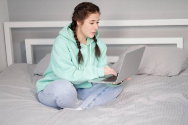 Uzaktan kumandalı ya da evden uzak çalışmalı. Yatakta dizüstü bilgisayarlı esmer bir kadın. Karantina kısıtlamaları. covid-19 salgını