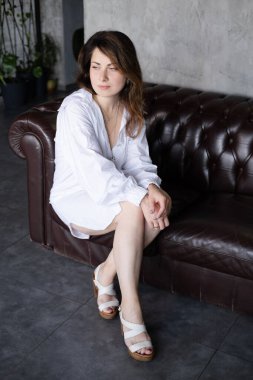 Deri koltukta beyaz gömlekli esmer kadın.