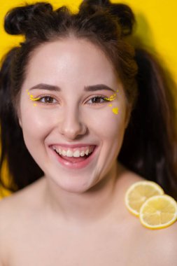 Sarı arka planda limonlu esmer kadın. Lezzetli meyve. Tropik meyveler, sağlıklı yiyecekler. Turunçgil dilimi