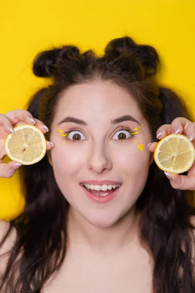 Brunette woman girl with lemon near skin face on yellow background. tasty juicy fruit. Tropical fruits, Healthy food. citrus slice — Stock Photo, Image