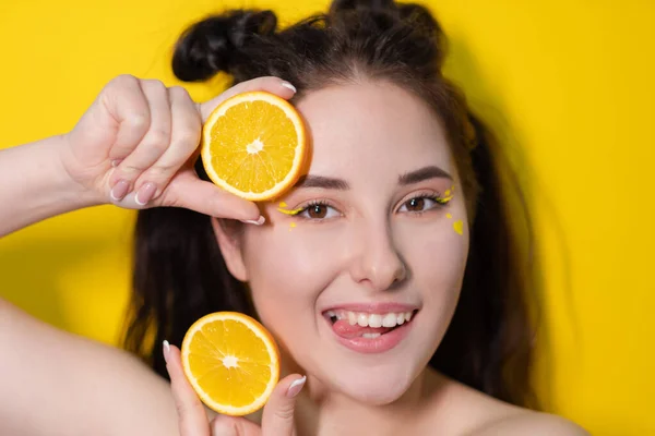 Young brunette woman girl with slice of orange fruit near skin face on yellow background. tasty juicy fruit. Tropical fruits, Healthy food. citrus slice. tasty juicy fruit — Stock Photo, Image