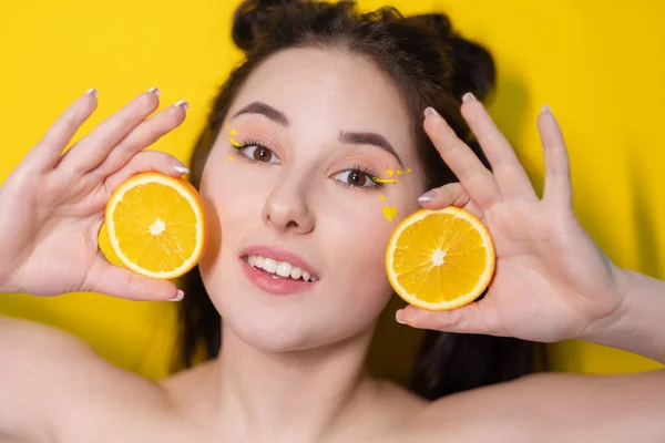 Young brunette woman girl with slice of orange fruit near skin face on yellow background. tasty juicy fruit. Tropical fruits, Healthy food. citrus slice. tasty juicy fruit — Stock Photo, Image