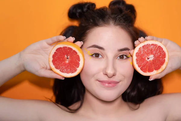 Chica joven con rodaja de pomelo sobre fondo naranja — Foto de Stock