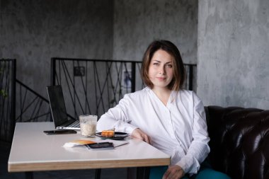 Kafede beyaz bluzlu bir kadın bir fincan kahve ve tatlı ile. Kahve molası. iş kadını.