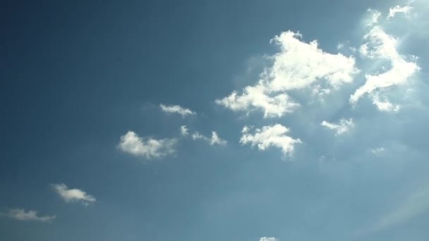 Weiße Wolken fliegen über einen strahlend blauen Himmel. Klarer Himmel an einem sonnigen Sommertag. Frühling Wolkenlandschaft Hintergrund. Sonne, die auf Sommerhozizon in lebendigem Sonnenlicht scheint. Kopierraum — Stockvideo