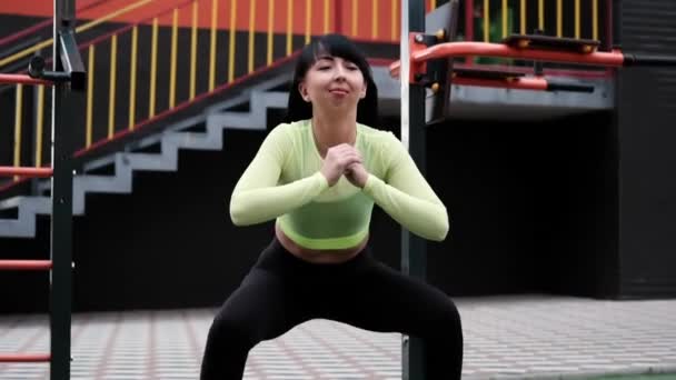 Femme sportive en noir et vert vêtements de sport faire des exercices de sport à l'extérieur sur l'aire de jeux de sport. corps mince et sain parfait. — Video