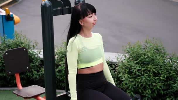 Mujer deportiva en ropa deportiva negra y verde haciendo ejercicios deportivos fuera en el patio de recreo deportivo. cuerpo delgado sano perfecto. — Vídeo de stock