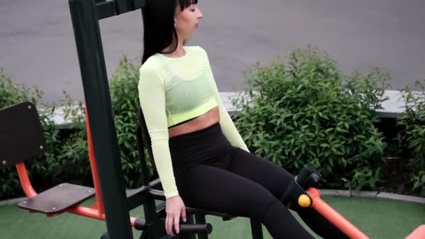 Sportieve vrouw in zwarte en groene sportkleding die buiten sport doet op de sportspeelplaats. perfect gezond slank lichaam. — Stockvideo