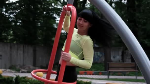 Sportig kvinna i svarta och gröna sportkläder gör sport övningar utomhus på sport lekplats. perfekt frisk smal kropp. — Stockvideo