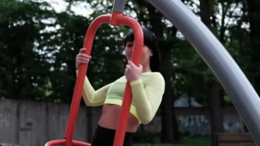 Güzel esmer, modaya uygun spor giyimli bir kadın dışarıda spor egzersizleri yapıyor. Mükemmel ince vücut..