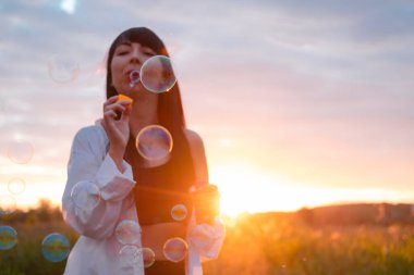 Çekici esmer kadın gün batımında sabun köpüğü yapıyor..