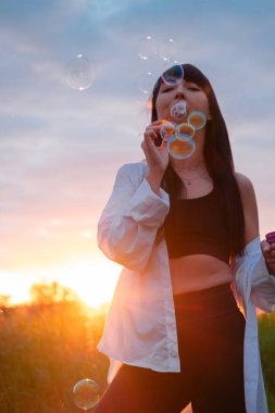 Çekici esmer kadın gün batımında sabun köpüğü yapıyor..