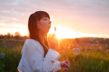 Çekici esmer kadın gün batımında sabun köpüğü yapıyor..
