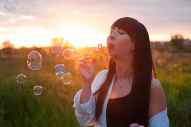 Çekici esmer kadın gün batımında sabun köpüğü yapıyor..