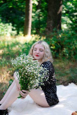 Beyaz kır çiçekleriyle dolu çekici sarışın bir kızın portresi. Çiçekli kadın.