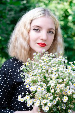 Beyaz kır çiçekleriyle dolu çekici sarışın bir kızın portresi. Çiçekli kadın.