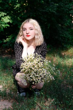 Beyaz kır çiçekleriyle dolu çekici sarışın bir kızın portresi. Çiçekli kadın.