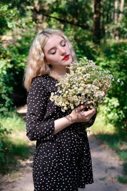 Beyaz kır çiçekleriyle dolu çekici sarışın bir kızın portresi. Çiçekli kadın.