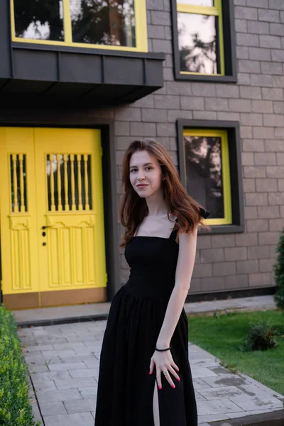 Щаслива Молода Жінка Чорній Сукні Перед Сучасною Будівлею Жовтими Дверима — стокове фото