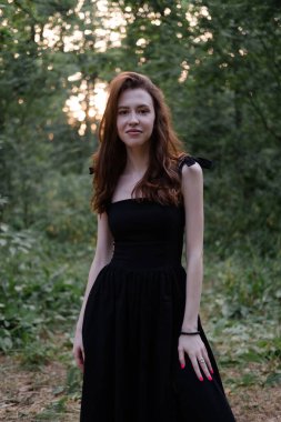 Siyah elbiseli çekici esmer kadın ormanda poz veriyor. Özgürlük. moda portresi.