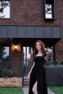 Yeni evinin yanında kendine güvenen bekar bir kadın. Kahverengi ve siyah modern bina. Kaygısız varoş hayatı.