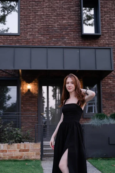 Yeni evinin yanında kendine güvenen bekar bir kadın. Kahverengi ve siyah modern bina. Kaygısız varoş hayatı.