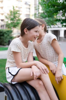 Çocuklar yeni renkli ekipmanlarla modern oyun bahçesinde eğleniyorlar. Kardeşlik, arkadaşlık. Dışarıda oynayan iki güzel kız. kız kardeş, kankalar, arkadaşlar.