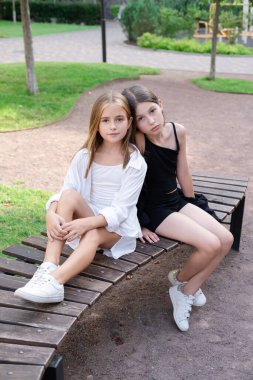 happy and lucky to have a sister. two girls outdoors in black and white clothes. good and bad. obedient and harmful. fraternal twins teen sisters