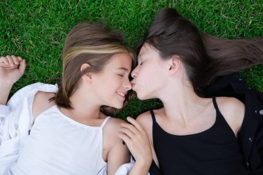Outdoors closeup portrait of two adorable children share love and friendship. Two sisters having fun on sunlight and nature background. Happy family concept. Two girls twins in the park in summer.