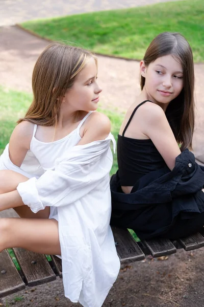 fraternal twins sisters. blonde and brunette teen girls in fashionable black and white clothes outdoors. sisterhood, siblings spending time together