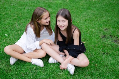 Dışarıda iki sevimli çocuğun yakın plan portresi aşkı ve arkadaşlığı paylaşıyor. Güneş ışığı ve doğa geçmişiyle eğlenen iki kız kardeş. Mutlu aile kavramı. Yazın parkta iki kız ikiz..