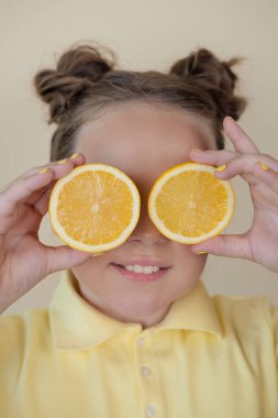 Sarı arka planda olgun limon dilimleri olan çekici bir genç kız. Meyve konsepti. yaz.