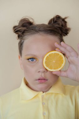 Sarı arka planda olgun limon dilimleri olan çekici bir genç kız. Meyve konsepti. yaz