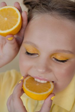 Sarı arka planda olgun limon dilimleri olan çekici bir genç kız. Meyve konsepti. yaz