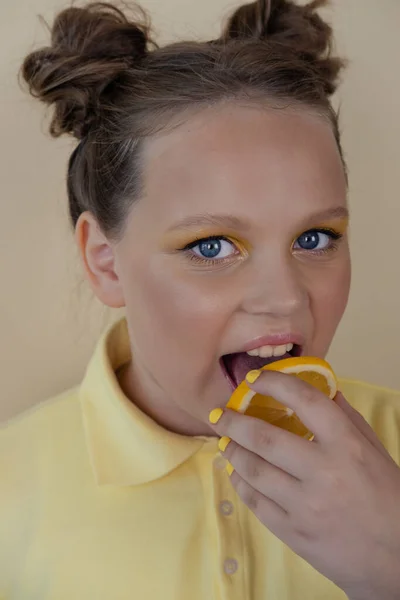 Γοητευτικό κορίτσι με φέτες ώριμου λεμονιού σε κίτρινο φόντο. ζουμερό φρούτο. καλοκαίρι — Φωτογραφία Αρχείου