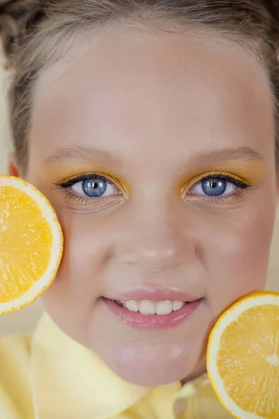 Kleuter meisje met citroen op gele achtergrond. kind met fruit — Stockfoto