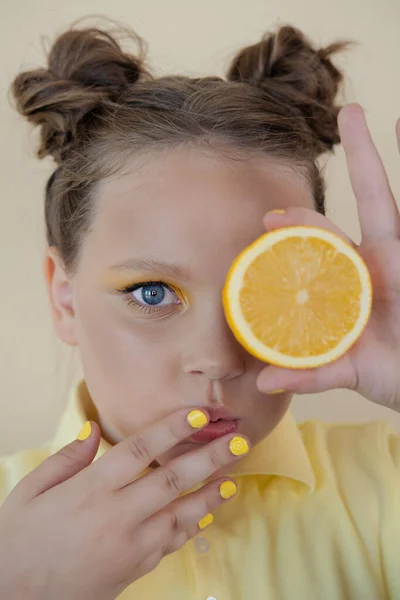 Sladký roztomilý dívka školní věk drží zralé čerstvé citron na žlutém pozadí. dítě s ovocem na barevném pozadí. letní citrusové jídlo — Stock fotografie