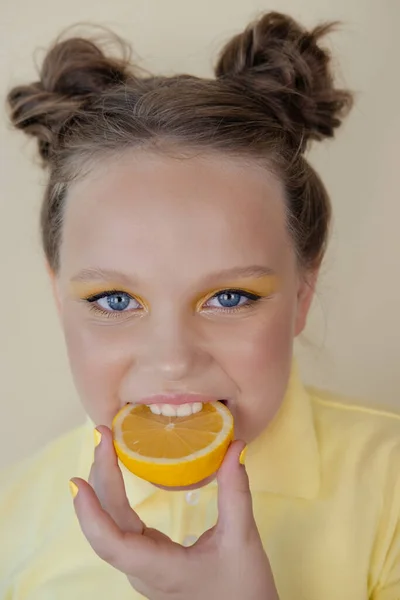 Kleuter meisje met citroen op gele achtergrond. kind met fruit — Stockfoto