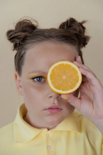 Preteenager girl with lemon on yellow background. child with fruit — Foto de Stock
